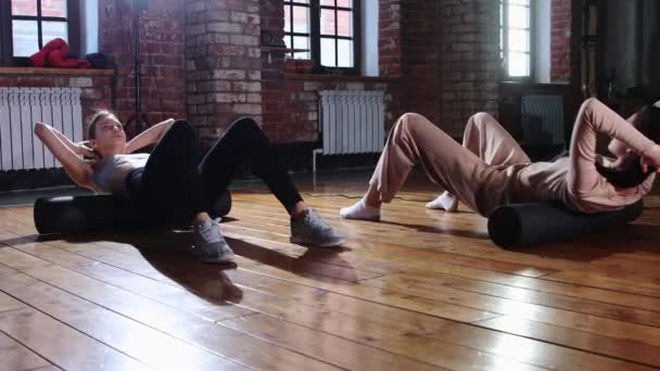 Sport - kvinnor tränar tillsammans i gymmet - gör övningar för ryggen med hjälp av en mjuk roller — Stockvideo