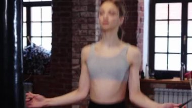 Spor salonunda idman yapan sıska bir kadın. İpin üzerinden atlıyor.