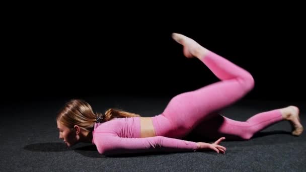 Gimnasia - Una joven mujer de plástico se acuesta en el suelo y dobla las piernas a la cabeza — Vídeos de Stock