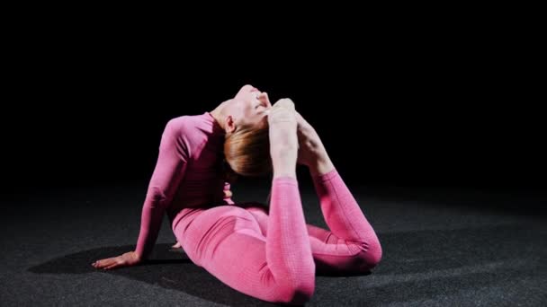 Gymnastiek - Een jonge plastic vrouw ligt op de vloer en het uitvoeren van oefeningen — Stockvideo
