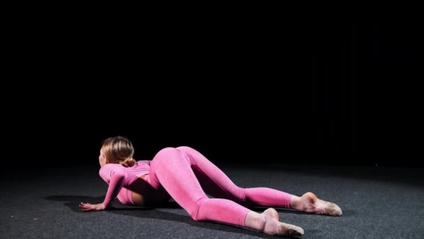 Gimnasia - mujer joven en traje rosa realizando ejercicios de plástico para su espalda en el suelo — Vídeos de Stock