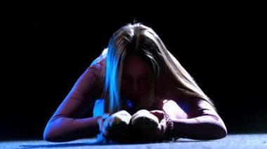 Jimnastik - pembe kostümlü genç bir kadın yerde oturuyor ve ısınıyor - neon ışıklı