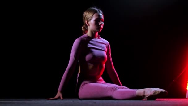 Gimnasia - joven mujer de plástico en traje rosa realizando un ejercicio - iluminación de neón rojo — Vídeo de stock