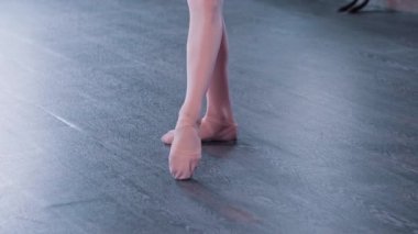 Dans stüdyosunda antrenman yapan bir balerin kız bacak pozisyonunda duruyor.