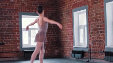 Gülümseyen bir balerin kız stüdyoda dans ediyor.