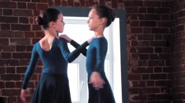 İki balerin kız stüdyoda siyah kostümlerle dans ediyor.