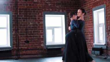 Stüdyoda uzun siyah kostümlerle dans eden iki balerin kız.