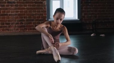 Bale dansı. Yerde oturan ve sivri uçlu ayakkabı giyen küçük bir kız.