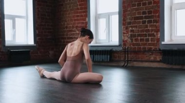 Bale dansı - küçük bir kız balerin esneyerek yerde oturuyor