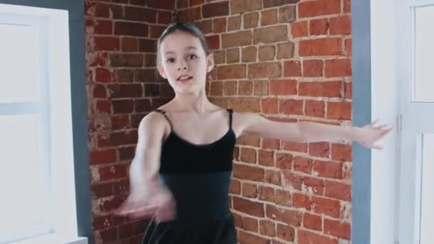 Ballett tanzen drinnen - ein kleines Mädchen tanzt im schwarzen Anzug beim Training — Stockvideo