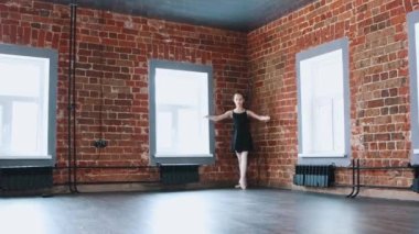 İçeride bale yapan küçük bir jimnastikçi kız stüdyonun köşesinden siyah takım elbiseyle dans ediyor.