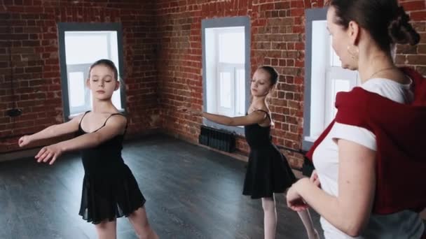 Baletní taneční trénink - dvě holčičky v černých oblecích na tréninku před zrcadlem se svým trenérem — Stock video