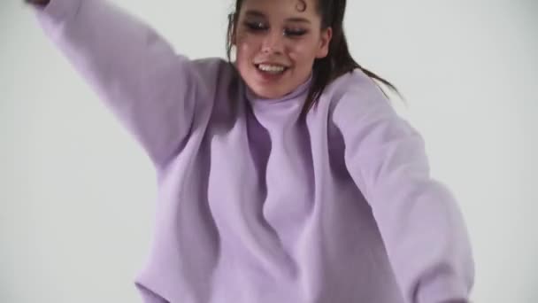 Danse - modèle jeune femme élégante en sweat à capuche violet freestyle danse sur fond blanc — Video