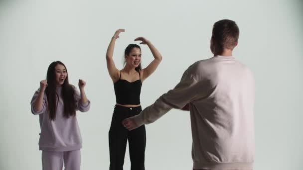 Taniec - młoda grupa tańczących - mężczyzna pokazujący taniec przenosi się do dwóch kobiet - bawiąc się — Wideo stockowe