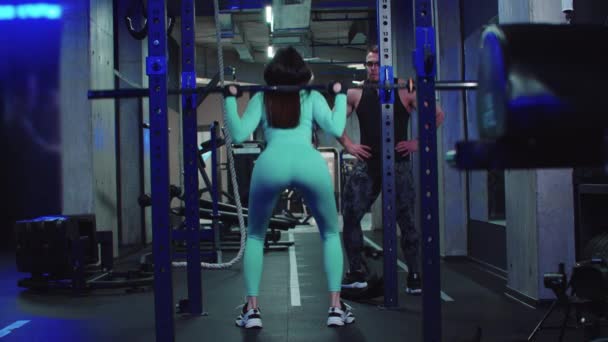 Woman trains her butt with dumbbells under the supervision of a trainer — Stok video