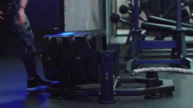 Erkek bir vücut geliştirici kilosunu değiştirip üzerinden atlıyor. Spor salonunda antrenman yapıyor.
