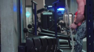 Güçlü vücut geliştiren adam kilo değiştiriyor ve üzerinden atlıyor. Spor salonunda antrenman yapıyor.