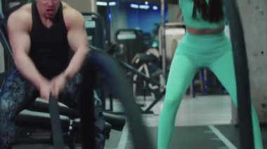 Erkek ve kadın ellerinde bir iple çapraz egzersiz yapıyorlar.