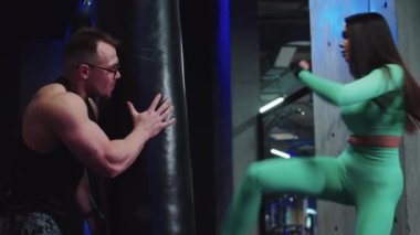 Koçla boks antrenmanı yapan bir kadın kum torbasına vuruyor.