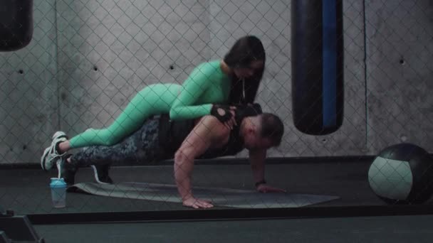 Un hombre haciendo flexiones con una mujer en la espalda — Vídeo de stock