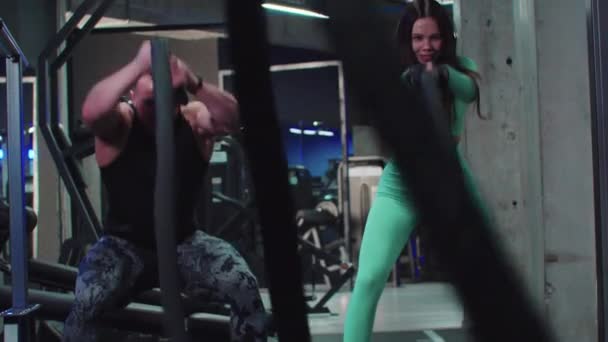 Entrenamiento en el gimnasio - hombre y mujer haciendo un ejercicio crossfit para manos músculos con una cuerda — Vídeo de stock
