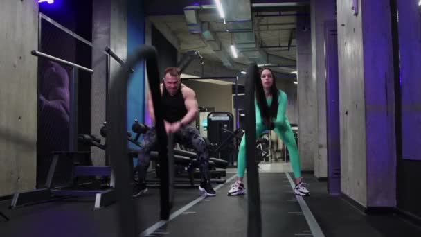 Gym training - sportive man and woman doing a crossfit exercise for hands muscles with a rope - endurance training — Wideo stockowe