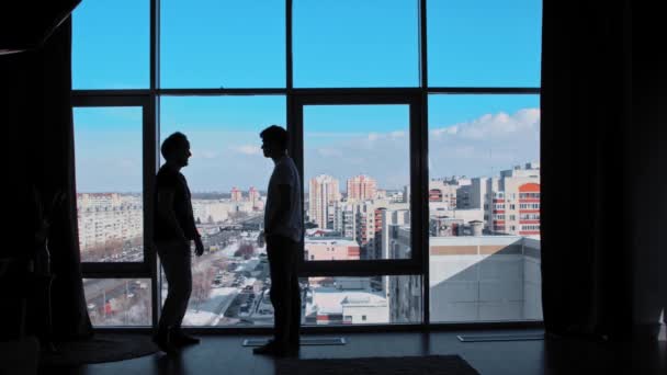 Dois homens ficam no escritório com janelas panorâmicas, discutem e começam uma briga — Vídeo de Stock