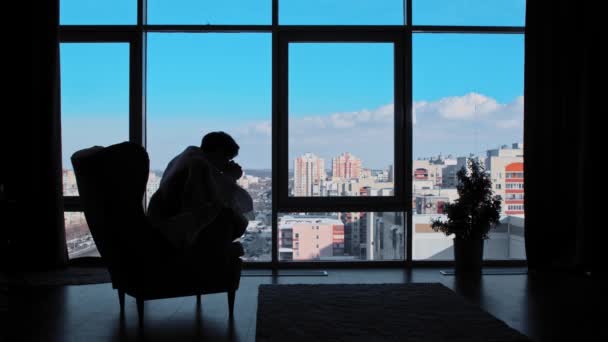 Geschäftsmann im Karo sitzt im Büro und trinkt Kaffee aus einem Becher - Blick in die Panoramafenster — Stockvideo
