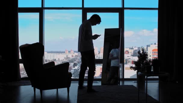 Egy üzletember integet a tükör előtt az irodájában, panoráma ablakokkal és fotózkodik a telefonján. — Stock videók
