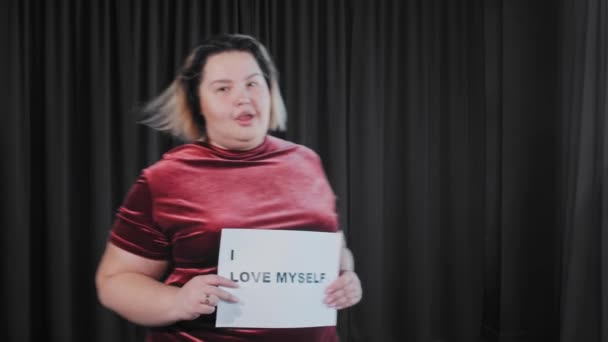 Уверенная флиртовая толстая женщина с табличкой с надписью I LOVE MYSELF — стоковое видео