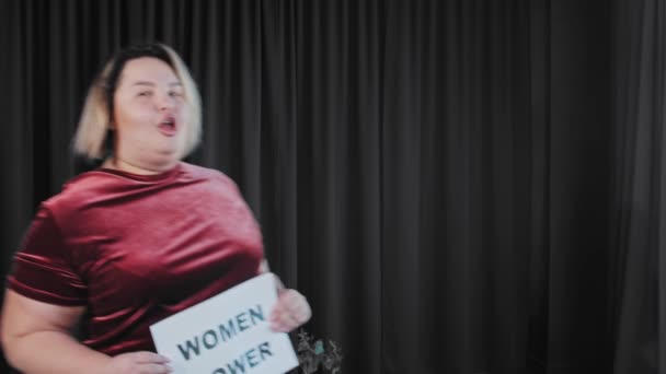 Una mujer gorda coqueta confiada sosteniendo una placa con un signo de poder de las MUJERES — Vídeo de stock