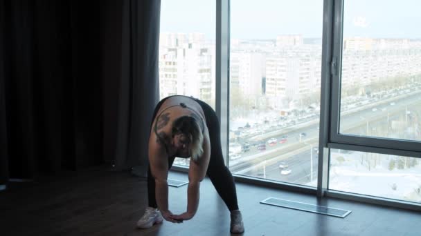 Μια υπέρβαρη γυναίκα που κάνει αθλητικές ασκήσεις στο στούντιο με πανοραμικά παράθυρα — Αρχείο Βίντεο