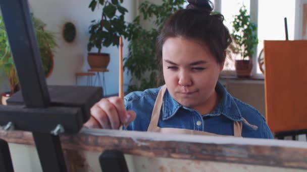 Een mollig indpired vrouw verf kunstenaar tekening een schilderij met een borstel — Stockvideo
