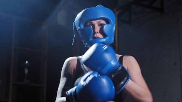 Татуированная женщина в защитном мягком шлеме надевает боксерские перчатки — стоковое видео