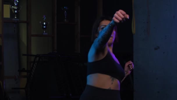Бокс в тренажерном зале - татуированная женщина показывает удары в неоновом освещении — стоковое видео