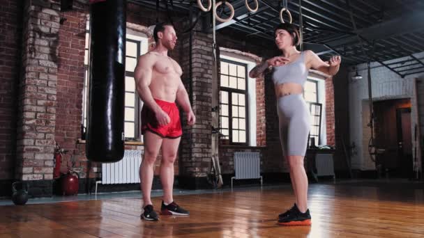 Hombre y mujer calentando sus cuerpos en el gimnasio — Vídeo de stock