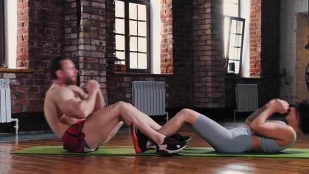Athletisch mann und frau pumpen ihre abs im die fitnessstudio — Stockvideo