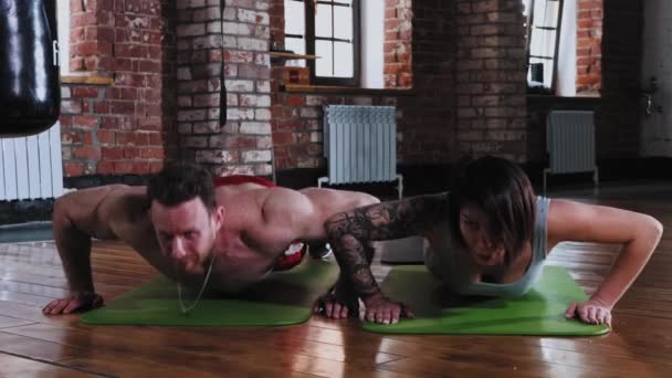 Atletische man en vrouw doen push-ups samen op yoga mat — Stockvideo