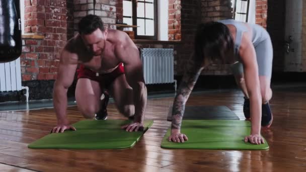Sportlicher Mann und Frau machen gemeinsam Liegestütze auf der Yogamatte und werden müde — Stockvideo