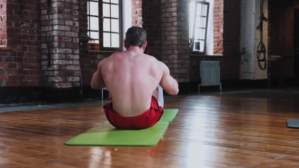 Een paar training in de sportschool - man pompen zijn buikspieren, terwijl de vrouw houdt zijn voeten — Stockvideo