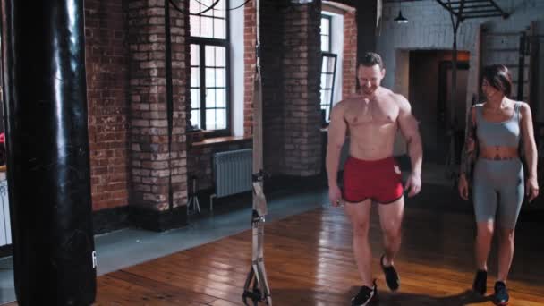 Pár trénink v tělocvičně - muž a žena vstupují do tělocvičny a začínají si ohřívat krk — Stock video