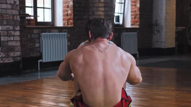 Kilka treningów na siłowni - mężczyzna pompujący mięśnie brzucha podczas gdy piękna dziewczyna trzyma jego stopy — Wideo stockowe