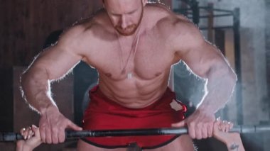 Çekici bir çift spor salonunda antrenman yapıyor. Bir kadın, kaslarını dambılla pompalamayı bitiriyor ve kameraya bakıyor.