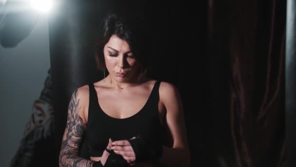 Татуйована жінка зв'язує руки перед тренуванням коробки і стоїть в бойовій позі — стокове відео
