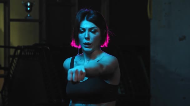 A strong tattooed woman showing karate fighting moves in neon lighting — Stock Video