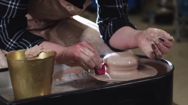 A woman removes the clay excess from a potters wheel with a sponge — Stock Video