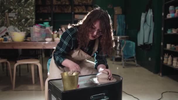 Bir kadın sanat stüdyosunda çömlekçi çarkında kil oluşturur. — Stok video