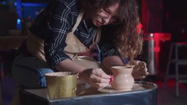 Çömlekçilik. Kıvırcık saçlı kadın. Küçük bir sünger kullanarak ıslak çamurdan basit bir kap yapıyor.