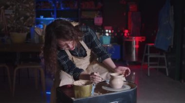 Çömlekçilik. Kıvırcık saçlı kadın. Yeni çömleğe mavi renk sürüyor.