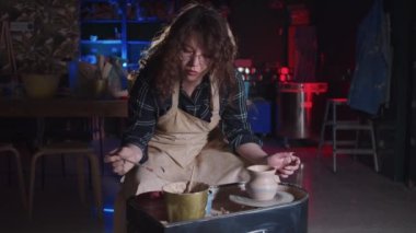 Çömlekçilik - kıvırcık saçlı kadın yeni çömleğe mavi ve kırmızı renkler sürüyor